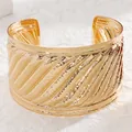Detailed close-up of wide golden cuff bracelet featuring relief wave patterns and metallic finish - 11 Kc Gold 4140 (pleated)