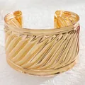 Detail view of bold golden cuff bracelet featuring oblique spiral textures and polished finish - 09 Kc Gold 5414 (glossy)