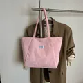 Pink corduroy tote bag with fashion label hanging on a rack in a lifestyle setting - Pink