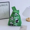 Green knit panda tote bag with Yumm text and single handle in a cozy home setting - Green - Five Pandas Pattern