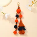 Dettaglio portachiavi boho con pompon di peluche, nappe a strati e moschettone dorato - Arcobaleno
