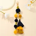 Dettaglio del portachiavi con pompon, perle in legno e nappe per borse a mano - Blu scuro