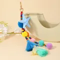 Dettaglio di portachiavi boho colorato con stella marina, pompon e nappe su un vaso - Celeste