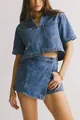 Detalle de top corto de mezclilla con cuello en V y falda cruzada con botones de metal - Top Único Azul