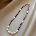 Halskette mit Lapis Lazuli und Süßwasserperlen auf Satinhintergrund mit Golddetails - Reis Süßwasserperle Lapislazuli Halskette