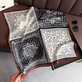 Detalle de bufanda de seda con estampado paisley negro y borde carmelo sobre cuero - FG52-2
