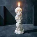 Detail of three stacked skulls soy wax candle with bright flame on dark background - White