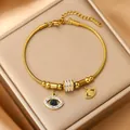 Macro-opname van goudkleurige roestvrijstalen armband met kristallen evil eye bedeltjes - Boze oog / Goud