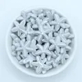 Close-up of glazed light blue starfish ceramic beads for DIY jewelry making in a white bowl - Gray