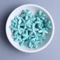 Macro detail of glossy blue starfish ceramic beads for DIY jewelry making in a white bowl - Turquoise Blue