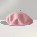 Close-up of a soft pink wool felt beret with a classic top stalk on a textured surface - One Size (56-59cm) / Pink
