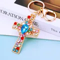 Golden cross keychain with colorful rhinestones and blue center gem on blue background - Sky Blue Crystal Cross (A792)