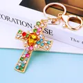 Cross-shaped keychain with gold finish and colorful rhinestones on a white book - Yellow Crystal Cross (A792)