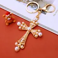 Gold cross keychain with intricate cutouts and white pearls on a warm festive background - White Pearl Cross (A902)