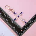 Blue crystal cross keychain with silver plating and rhinestones on pink background - Royal Blue Pearl Cross (A902)