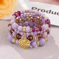 Detail of purple beaded bracelet stack featuring a gold heart pendant with I Love You engraving - Light Purple