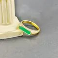 Minimalist gold titanium ring with a rectangular green agate inlay against a stone pillar - US 6