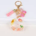 Detailed macro view of resin letter G keychain with dried flowers and pink tassel - Letter G
