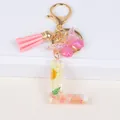 Floral resin letter L keychain with pink butterfly and tassel on white steps - Letter L