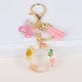 Detail of letter O keychain with dried yellow daisies, pink tassels and butterfly pendant - Letter O