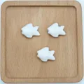 Dettaglio di tre perle a forma di pesce in ceramica bianca per gioielli fai-da-te - Bianco