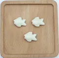 Vista dettagliata di tre perline a forma di pesce in ceramica crema per gioielli fai-da-te - Bianco Sporco