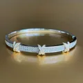 Dettaglio macro del bracciale bicolore con pavé di zirconi e motivi a X dorati - Stile Argento con Zirconi Rotondi e X Oro