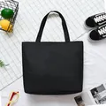 Minimalist black canvas tote bag shown with casual lifestyle props on a patterned surface - Blank Black