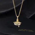 Macro shot of custom gold graduation necklace with engraved cap and yellow gemstone - L