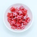 Top view of glossy red star-shaped ceramic beads for DIY jewelry making in a white bowl - Red