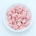 Macro shot of light pink star-shaped ceramic beads for DIY necklace making in a white bowl - Pink