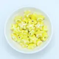 Close-up of glossy yellow star-shaped ceramic beads for handmade jewelry making - Yellow