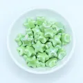 Close-up of grass green glazed ceramic star beads for DIY jewelry making in a white bowl - Green