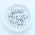 Macro view of blue star-shaped glazed ceramic beads with pre-drilled holes for DIY jewelry - Silver Grey