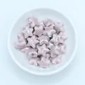 Macro shot of glazed lavender star-shaped ceramic beads in a white bowl for DIY jewelry - Dusky Pink