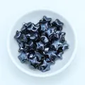 Macro view of metallic blue ceramic star beads for DIY jewelry making in a white bowl - Black