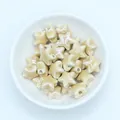 Macro detail of star-shaped ceramic beads with glossy cream glaze for DIY jewelry making - Light Coffee