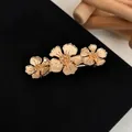 Elegant golden floral hair clip with three blooming flowers on a black textured surface - Golden Three Begonia Flower Spring Clip