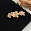 Elegant gold flower hair clip with three brushed finish blossoms on black background - Golden Magnolia
