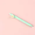 Pastel mint green retractable gel pen with white flower patch on pink background - Green