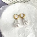 Detail of 18k gold plated hoop earrings with white baroque pearls on a minimalist background - Gold