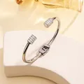 Macro shot of silver-tone steel bangle with shimmering crystal-studded ends on white stand - 68# Steel Color Sz600