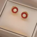 Detailed close-up of sunflower stud earrings with red marquise stones and gold finish - E1304-6