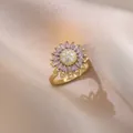 Rotating sunflower ring with purple petals and white crystals on champagne silk fabric - J0802-1