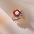 Detailed close-up of a rotating sunflower ring with red and white zircons on silk - J0802--5