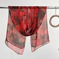 Red lightweight chiffon leaf print scarf draped over a metal bar in a studio setting - Red Black Leaf