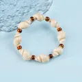 Handmade shell bracelet with brown beads and white seashells on a light blue background - 1739-03 Light Coffee Conch