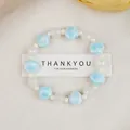 Blue star and white beaded ceramic bracelet shown on a white textured fabric background - Blue Shell Star Bead Style (1747-02) / Blue Shell