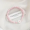 Pink ceramic beaded bracelet with white floral pendant on a minimalist white background - Flower Style (1747-01) / Pink