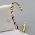 Detailed macro view of gold-plated twisted bangle with blue enamel and zircon stones - Sapphire Blue